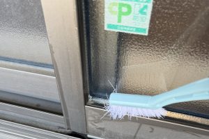 窓ガラス掃除で細かい場所をサッシブラシで掃除している様子